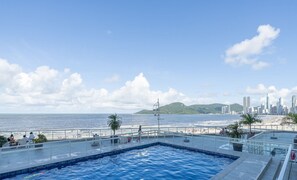 Une piscine sur le toit offrant une vue sur la plage et le paysage urbain.
