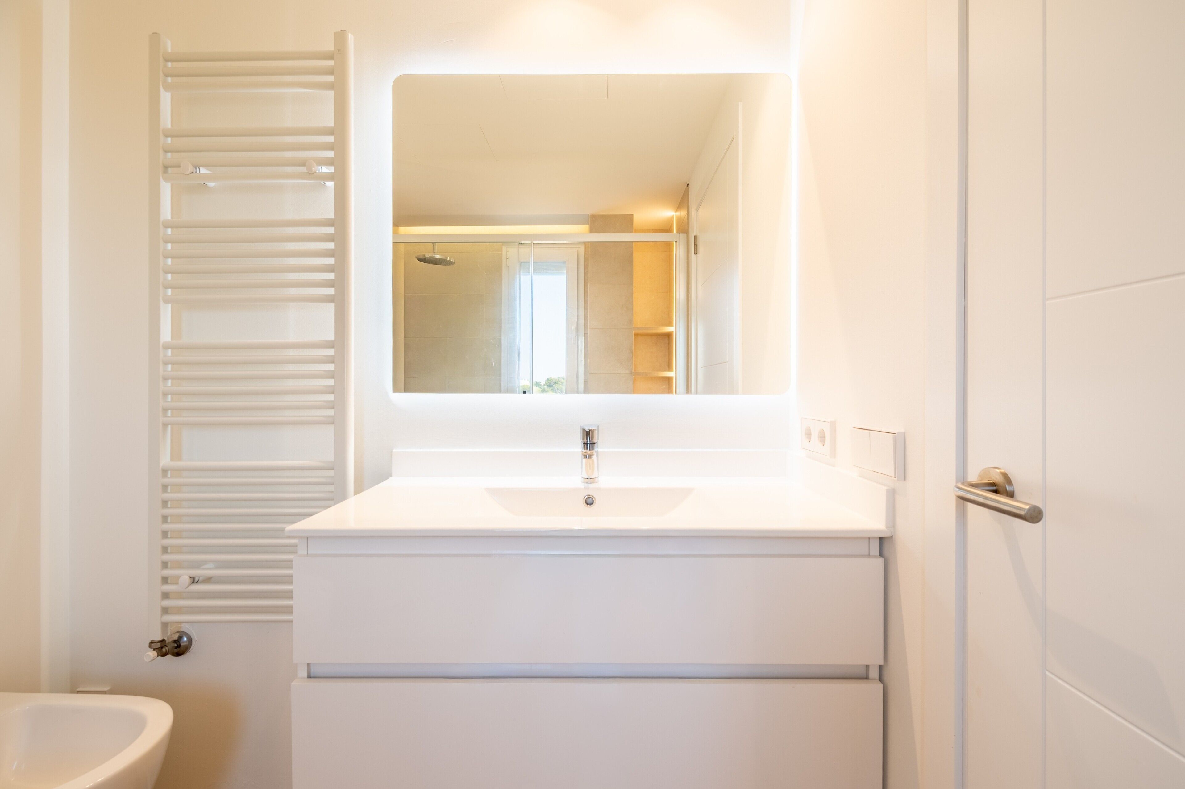 Une salle de bain avec un lavabo blanc, un miroir et un porte-serviettes.
