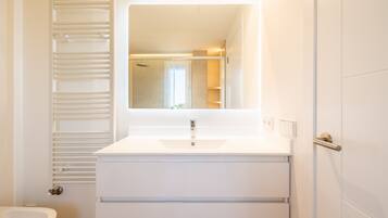 Une salle de bain avec un lavabo blanc, un miroir et un porte-serviettes.
