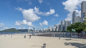 A beach with a volleyball net, a trash bin, and a flag.