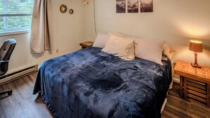 A bedroom with a bed, a chair, a nightstand, a lamp, and two wall art pieces. - Sugar Ski Premium Two Bedroom - Unit 825 (Sugar Mountain)