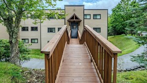 A wooden bridge leading to a building with a modern design, featuring multiple windows and a central entrance. - Sugar Ski Premium Two Bedroom - Unit 825 (Sugar Mountain)