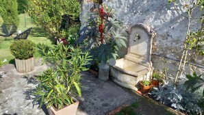 A garden with potted plants, a concrete bench, and a wall-mounted water fountain.
