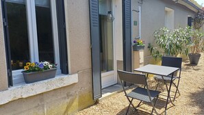 A building with a window, a door, and a small outdoor seating area with a table and chairs.