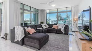 A modern living room with a sectional sofa, a coffee table, and a TV.