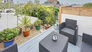 A rooftop patio with wicker furniture, potted plants, and a view of the cityscape. - Host & Stay | George Street Retreat (Brighton and Hove)