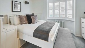 A bedroom with a bed, bedside tables, a radiator, a window with shutters, and a framed picture on the wall. - Host & Stay | George Street Retreat (Brighton and Hove)