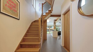 Eine hölzerne Treppe führt zu einer Zwischenebene mit einem gerahmten Zitat an der Wand.