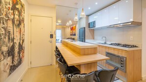 A modern kitchen with white cabinets, a central island, and a dining area with black chairs. - Apt w/ Balcony & BBQ 400m From Beach Dbr0805 (Itapema)