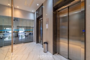 A modern elevator area with glass doors, a trash bin, and a digital display showing the floor number. - Apt w/ Balcony & BBQ 400m From Beach Dbr0805 (Itapema)