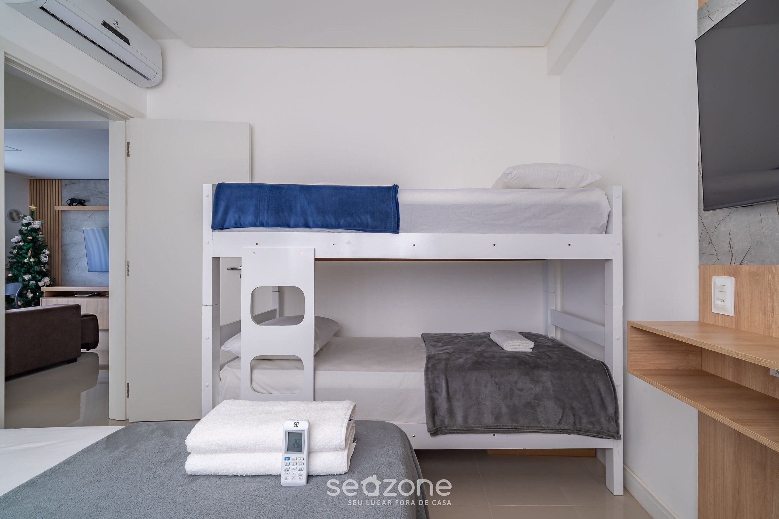 A bunk bed room with a digital thermostat, a small table with a towel, and a TV on the wall.