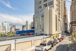 A street view with parked cars, a building with a sign, and high-rise buildings in the background. - Apt w/ Balcony & BBQ 400m From Beach Dbr0805 (Itapema)