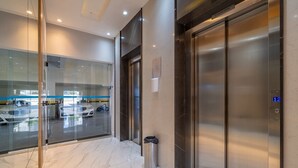 A modern elevator area with glass doors, a trash bin, and a digital display showing the floor number. - Apt w/ Balcony & BBQ 400m From Beach Dbr0805 (Itapema)