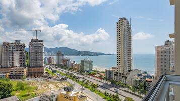 A coastal cityscape with high-rise buildings, a clear sky, and a view of the sea.