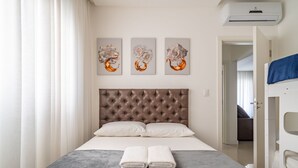 A neatly arranged hotel room with a tufted headboard, a bed with white linens, and three abstract paintings on the wall. - Apt w/ Balcony & BBQ 400m From Beach Dbr0805 (Itapema)