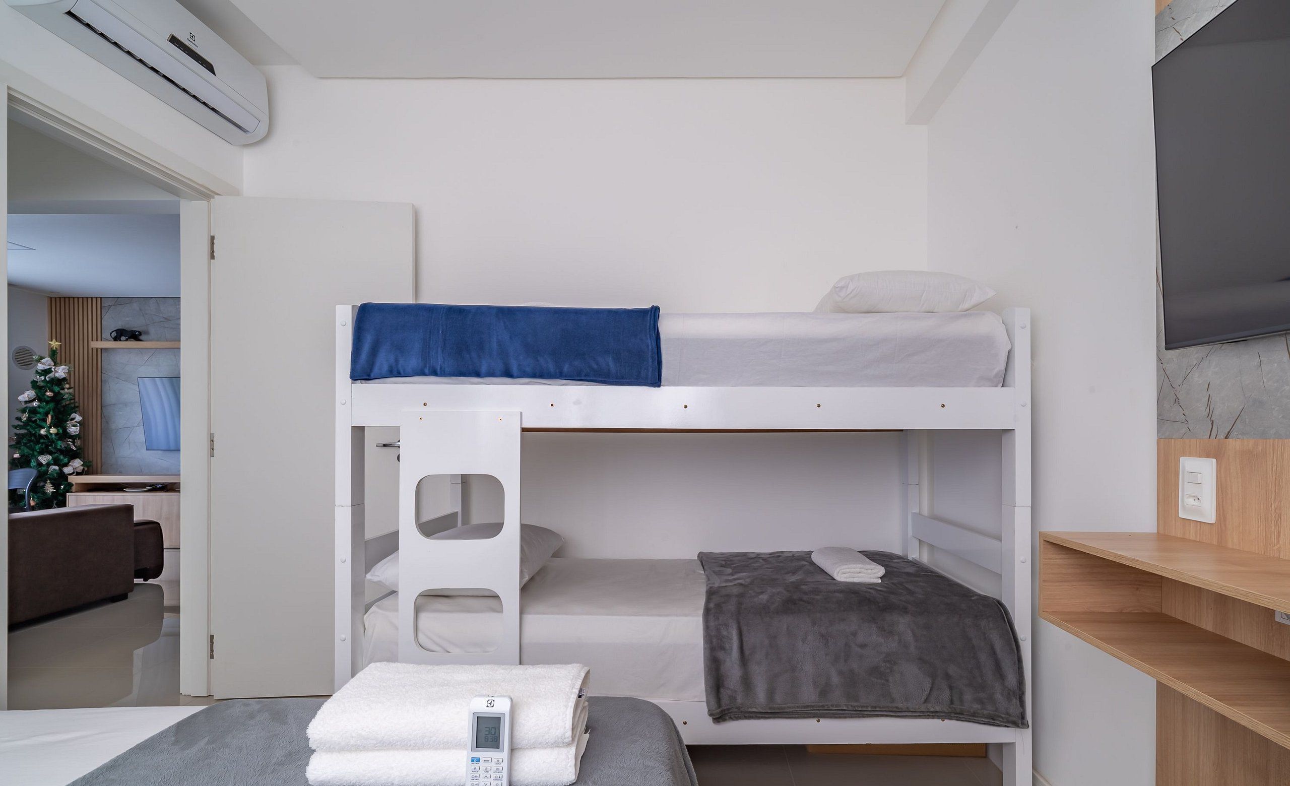 A bunk bed room with a digital thermostat, a small table with a towel, and a TV on the wall.