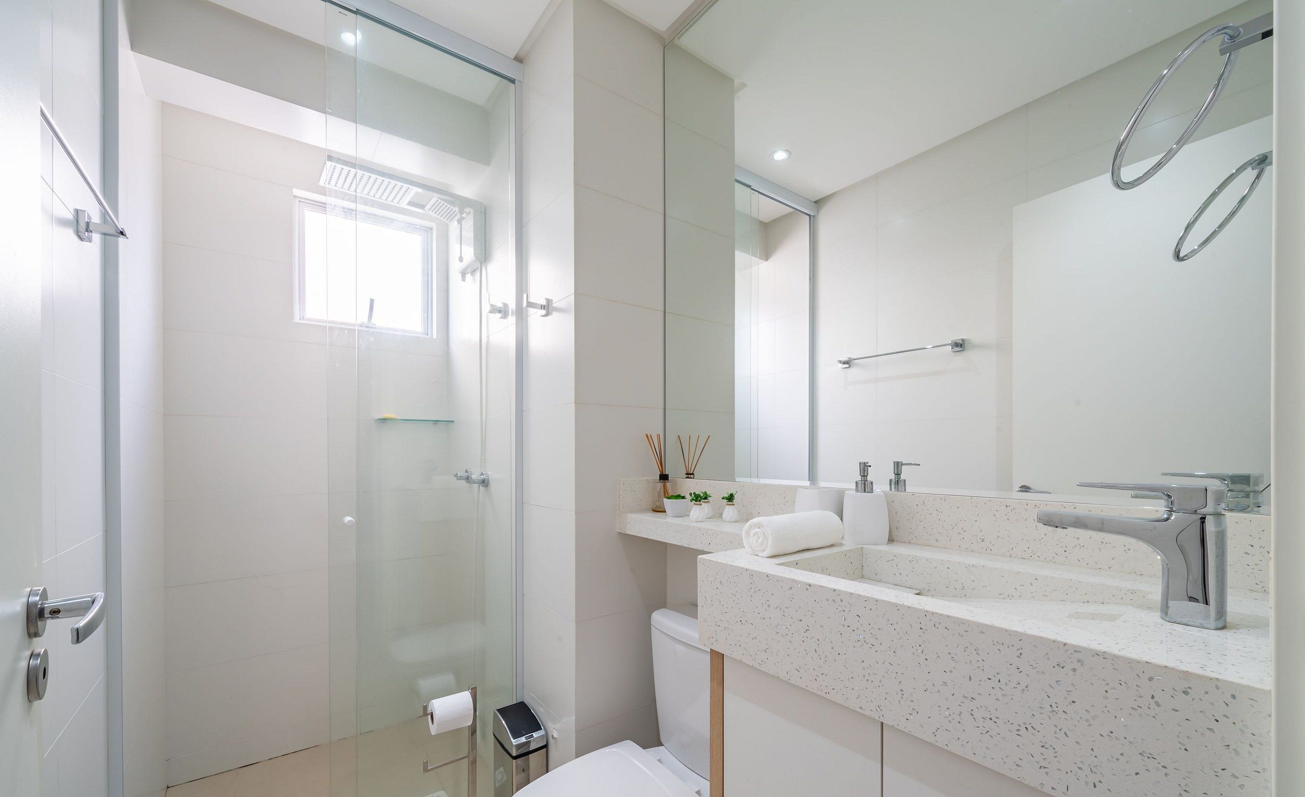 A modern bathroom with a glass shower enclosure, a white sink with a mirror, and a toilet.