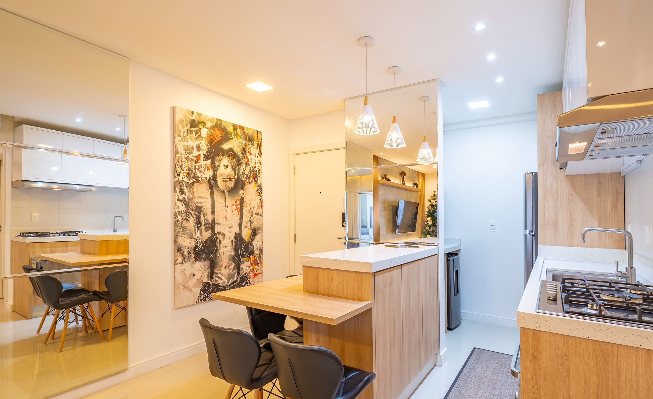 A modern kitchen with a central island, a dining area with chairs, and a large abstract painting on the wall.