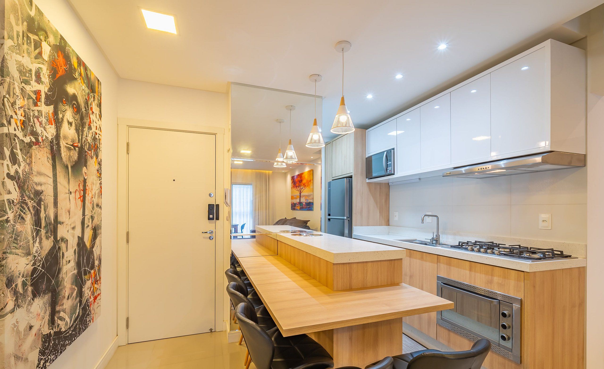 A modern kitchen with white cabinets, a central island, and a dining area with black chairs.
