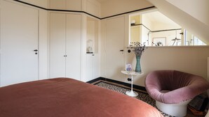 A bedroom with a large bed, a chair, a small table with a vase, and a wardrobe. - Luxurious, quiet, bright studio in the heart of the south of Pigalle (Paris)