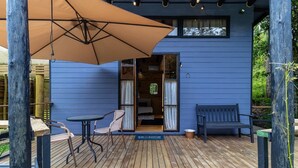 A wooden deck with a bench and chairs, a large umbrella, and a sign reading "SEIZONE".
