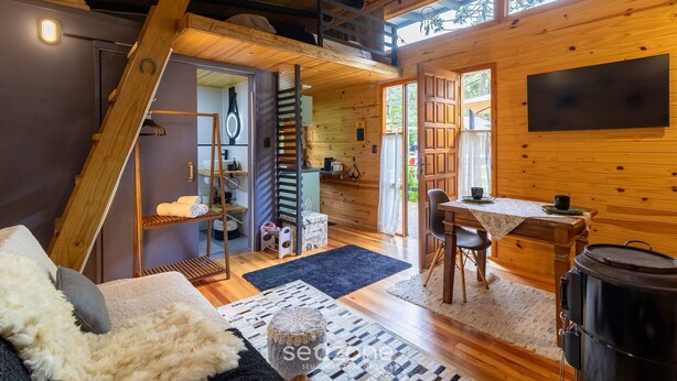 A cozy cabin interior with a loft bedroom, a dining area, and a kitchen.
