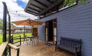 A wooden deck with a table and chairs, a bench, and a large umbrella. - Cabin in the Avencal Waterfall Valley Cua001 (Urubici)