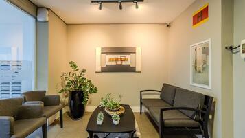 A modern living room with a sofa, chairs, a coffee table, and a potted plant.