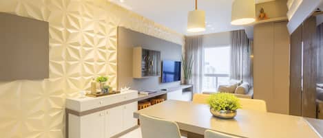 A modern kitchen with a dining area, featuring a geometric wall pattern, a central island, and pendant lighting.
