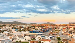 A coastal cityscape with a mix of residential and commercial buildings, a prominent port with cranes, and a clear sky. - Beautiful Apartment in Itajai Ctp1103 (Itajai)