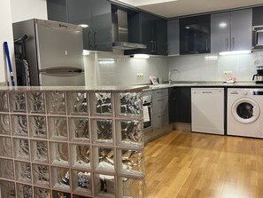 A modern kitchen with stainless steel appliances, a built-in oven, and a washing machine. - Bright Two-Bedroom Apartment in Maragall (Barcelona)
