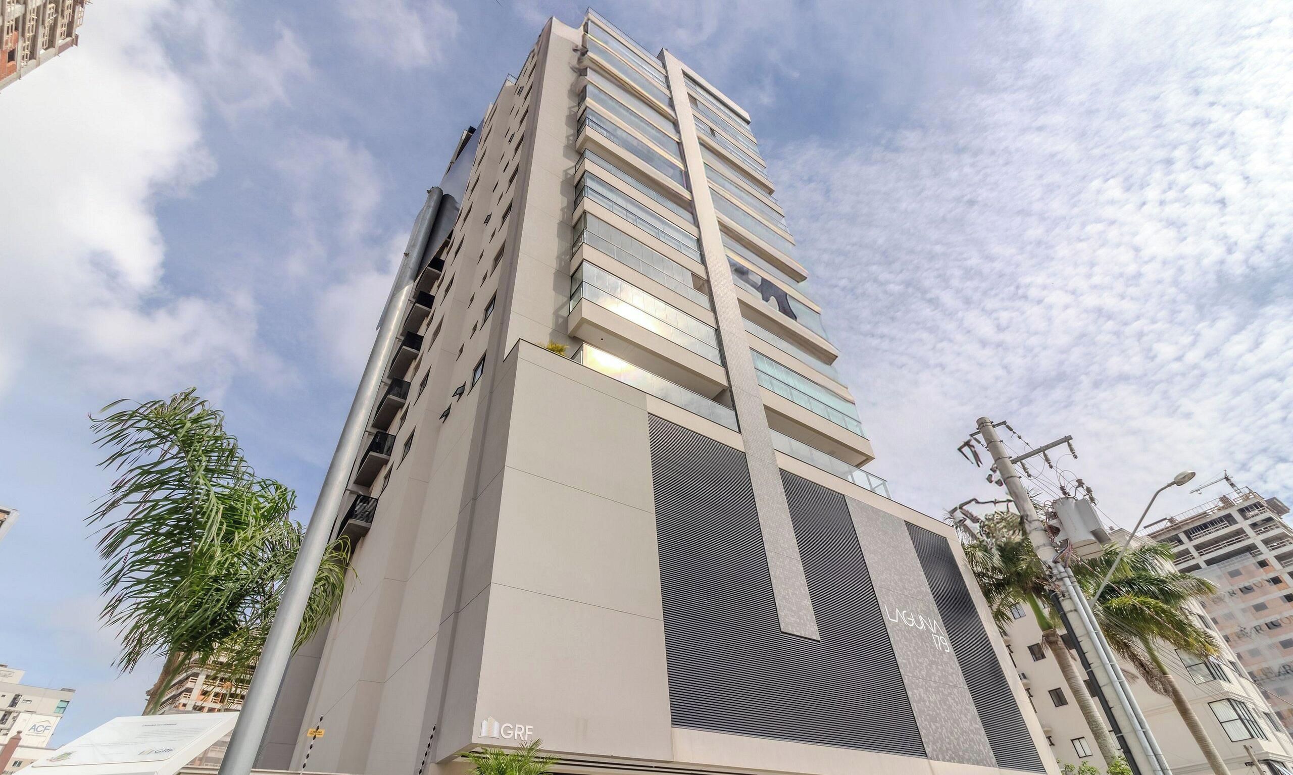 Un edificio de gran altura con un diseño arquitectónico moderno, que destaca un elemento vertical prominente y una fachada grande con textura.