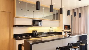 Een moderne keuken met een centraal eiland, zwarte hanglampen en een ingebouwde magnetron.