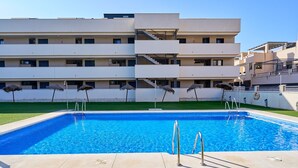 A swimming pool with a modern building in the background. - 2-Bedroom Penthouse with Sea Views, Wi-Fi, and Air Conditioning (Vélez-Málaga)