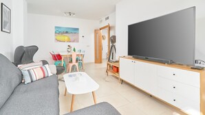 A living room with a sofa, a coffee table, a TV, and a dining area with chairs and a table. - 2-Bedroom Penthouse with Sea Views, Wi-Fi, and Air Conditioning (Vélez-Málaga)