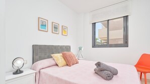 A bedroom with a bed, a bedside table with a mirror, a window with a view, and a chair. - 2-Bedroom Penthouse with Sea Views, Wi-Fi, and Air Conditioning (Vélez-Málaga)