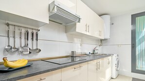 A modern kitchen with white cabinets, a black countertop, and a built-in washing machine. - 2-Bedroom Penthouse with Sea Views, Wi-Fi, and Air Conditioning (Vélez-Málaga)