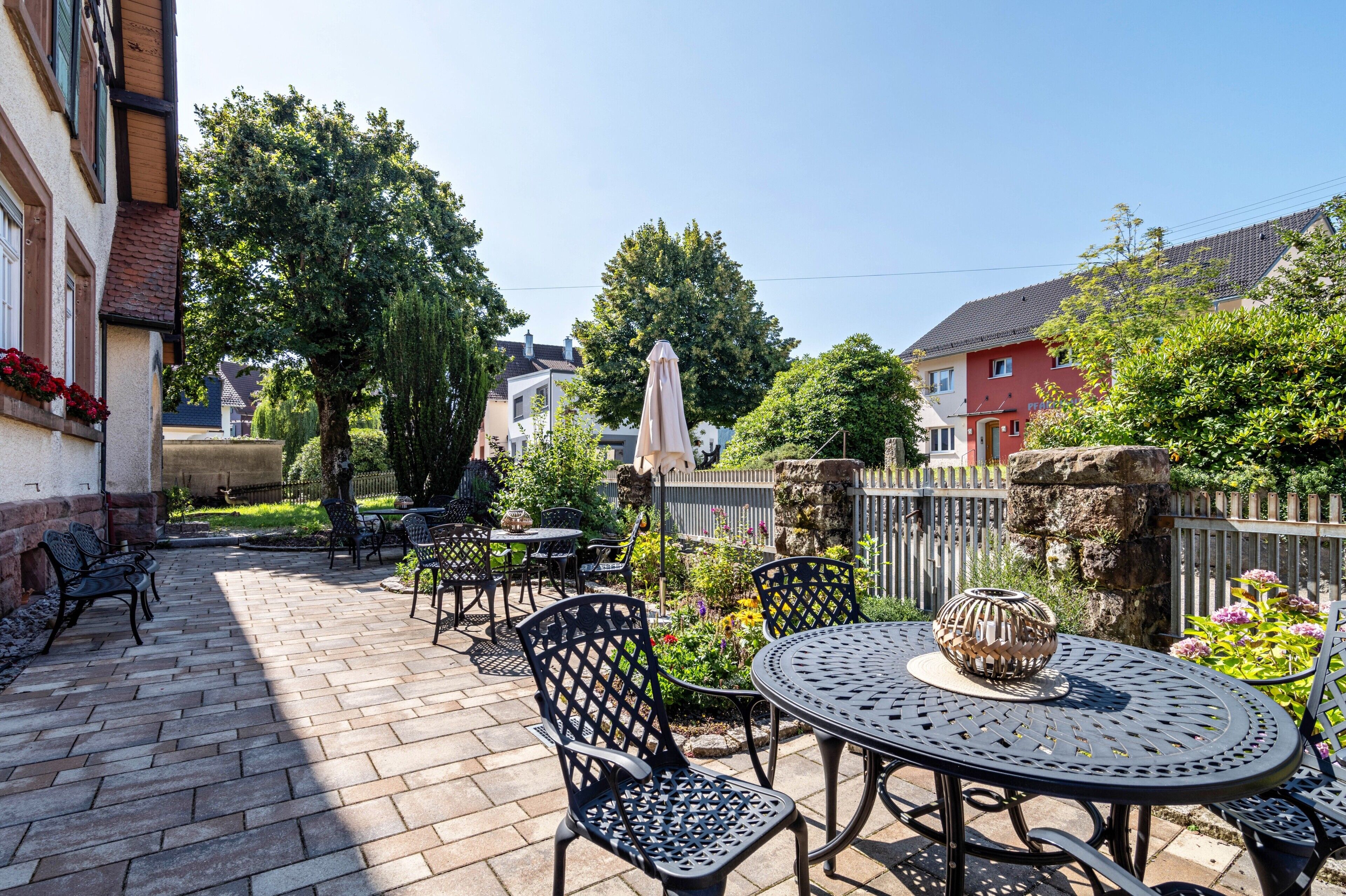 Une terrasse avec des sièges d’extérieur, une table ronde et un vase décoratif.