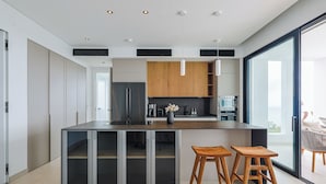 A modern kitchen with a central island, wooden cabinets, and a large window. - Villa Turquoise Heaven (Sint Maarten)