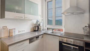 A modern kitchen with a dishwasher, stove, and large window.