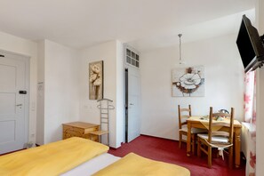 Une chambre avec deux lits, un bureau, une chaise, une table et un téléviseur.