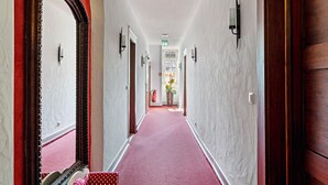 A hallway with a red carpet, wooden doors, and a large mirror on the left. - Room 'Schwarzwald 2' with Shared Terrace, Shared Garden and Wi-Fi (Forbach)