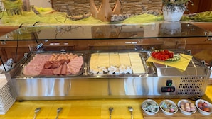 Een buffet met diverse vleessoorten, kazen, bestek en sauzen.