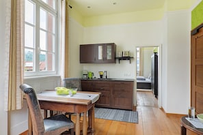 A kitchen with wooden cabinets, a dining table with chairs, and a view through an open door.