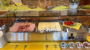 Buffet com diversos carnes e queijos, utensílios e acompanhamentos.