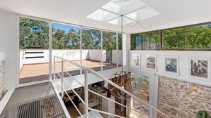 A spacious room with large windows, a skylight, and a staircase leading to an outdoor area.