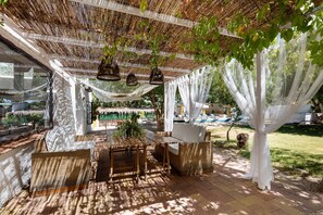 An outdoor patio with wicker furniture, a wooden table, and a hanging light fixture.