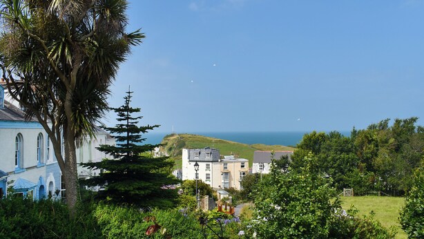 A coastal town with a prominent church, residential buildings, and lush gardens. - 3 bedroom accommodation in Ilfracombe (Ilfracombe)