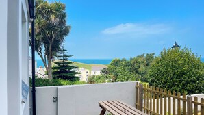 A wooden picnic table and bench in a balcony area with a view of the sea and buildings. - 3 bedroom accommodation in Ilfracombe (Ilfracombe)