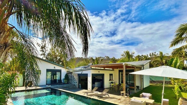 A modern pool area with a clear pool, wooden deck, and outdoor seating.